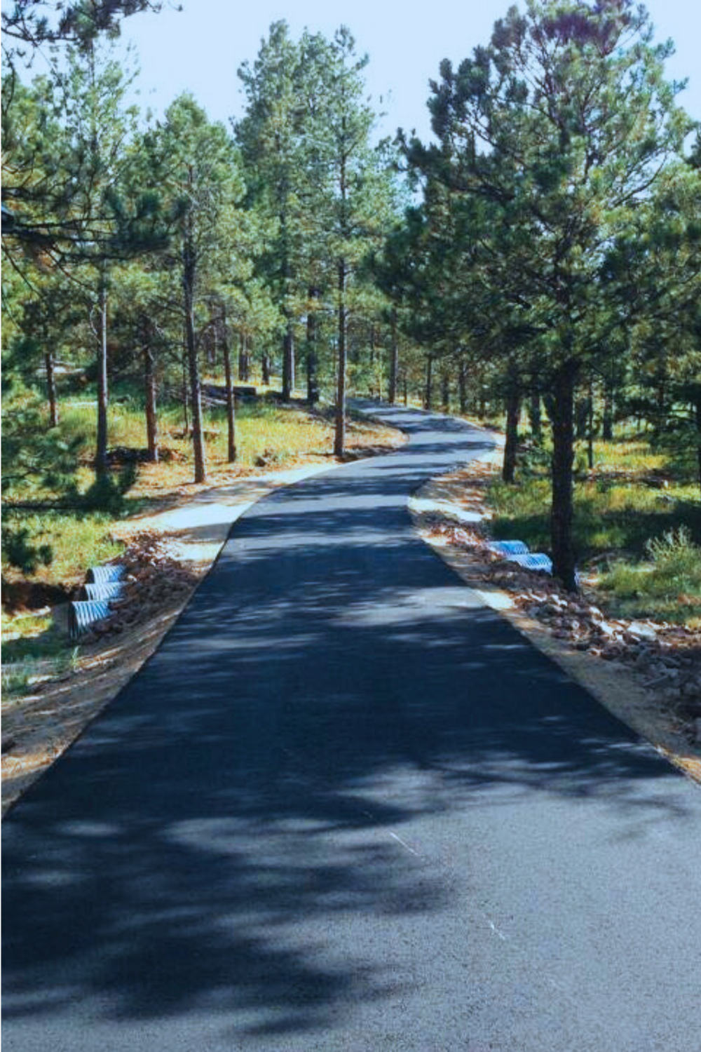 New 3.5 inch hot mix asphalt driveway with concrete culvert crossings and curb borders through Black Forest pines installed for Douglas County road division director by Dawley Asphalt Colorado Springs