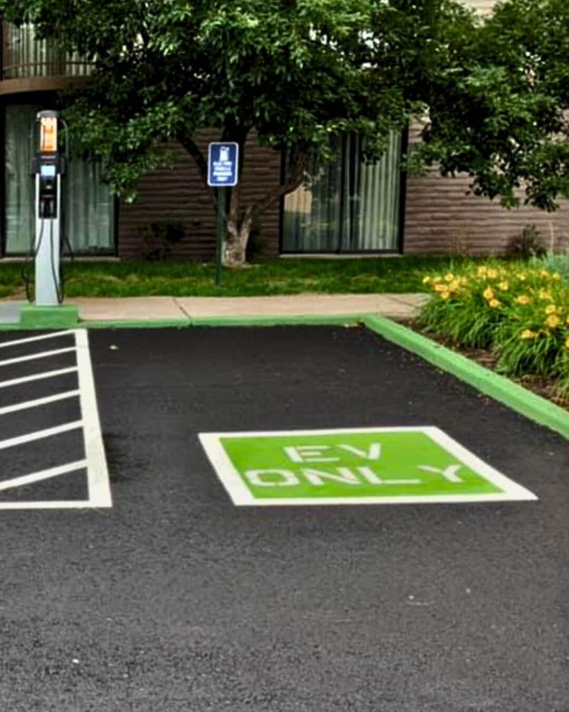 Freshly paved EV only parking spaces with green custom striping and active Level 2 charging station at Embassy Suites Colorado Springs by Dawley Asphalt