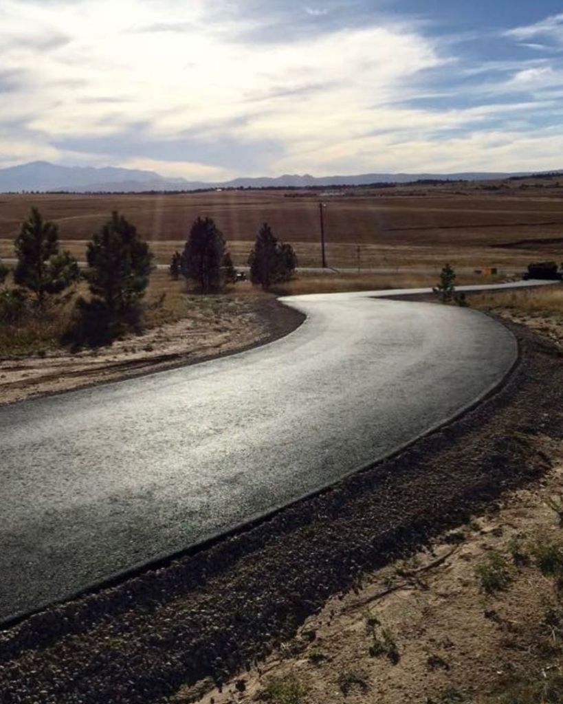 Newly installed 3.5 inch hot mix asphalt curved driveway across open plains terrain at Black Forest Colorado Springs with Front Range mountains visible on horizon by Dawley Asphalt
